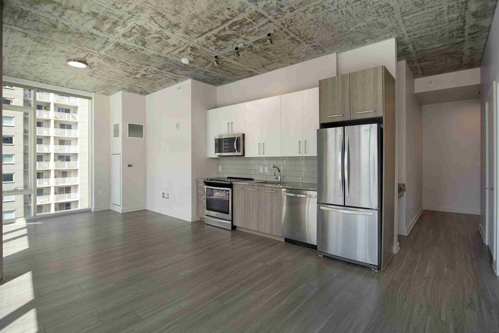 an empty kitchen with stainless steel appliances and white cabinets