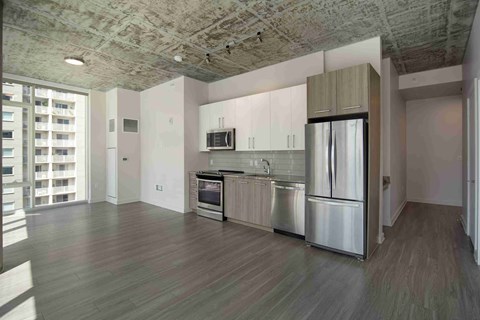 an empty kitchen with stainless steel appliances and white cabinets