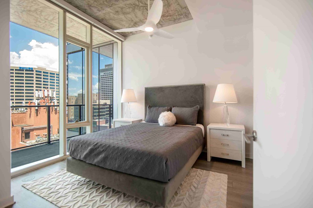 a bedroom with a bed and a ceiling fan and a large window