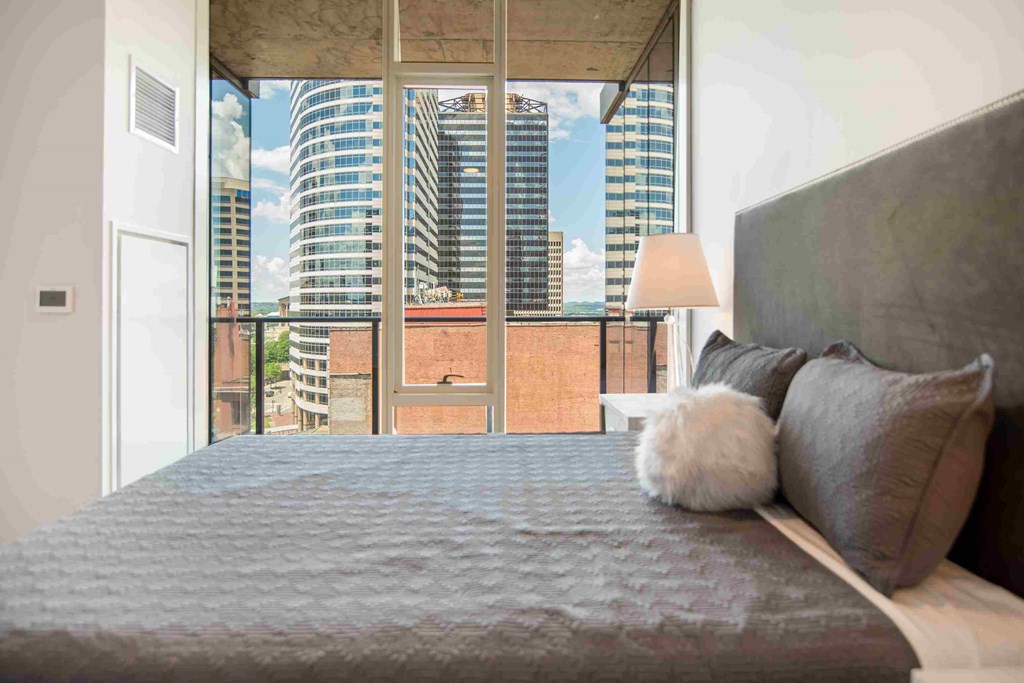 a bedroom with a large bed and a view of a city