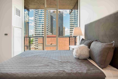 a bedroom with a large bed and a view of a city