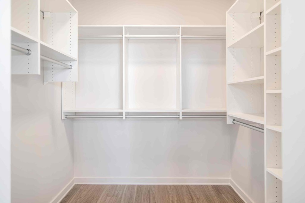 an empty walk in closet with white shelves and
