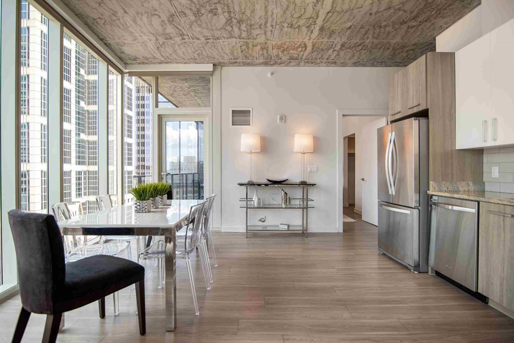 a dining room with a table and chairs and a kitchen with stainless steel appliances