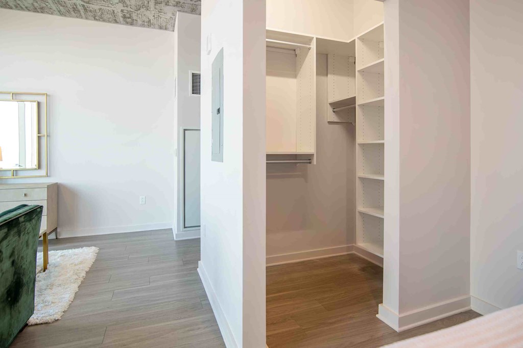 a walk in closet with a mirrored door in a bedroom