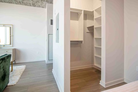 a walk in closet with a mirrored door in a bedroom