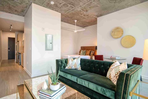 a living room with a green couch and a glass coffee table