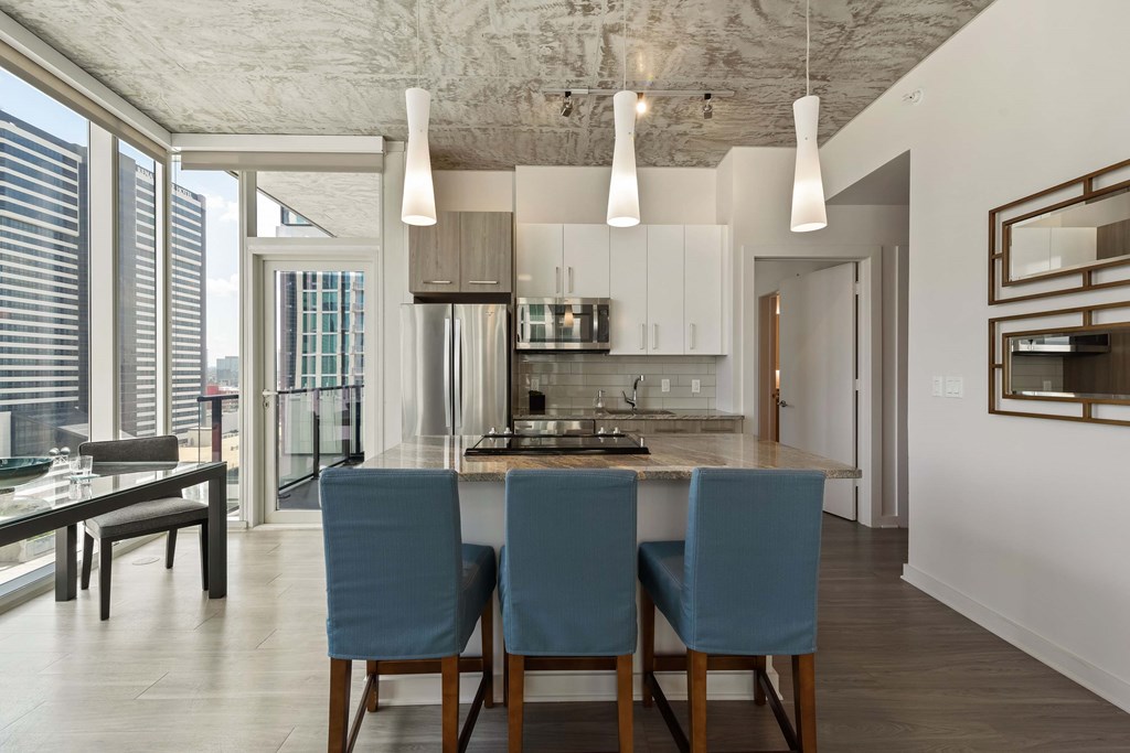 a kitchen with a marble counter top and blue chairs