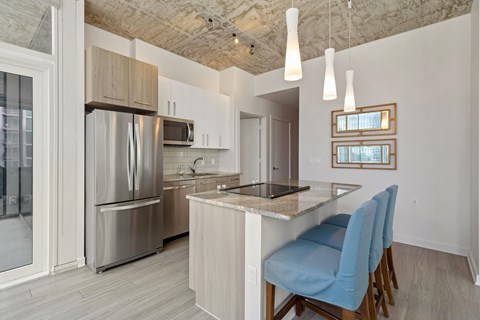 a kitchen with stainless steel appliances and a bar with blue chairs