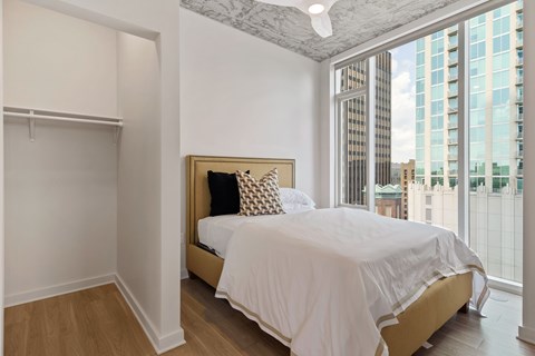 a bedroom with a large window and a bed with white sheets