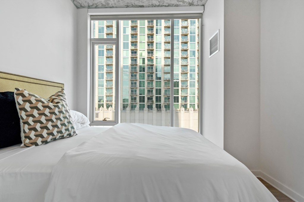 a bedroom with a large window and a white bed