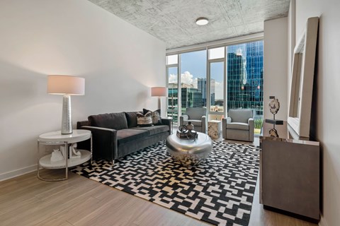 a living room with a large window and a black and white rug