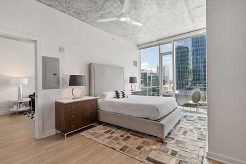 a bedroom with a bed and a large window and a city view
