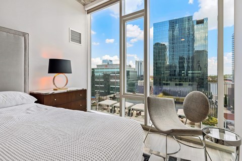 a bedroom with a bed and a view of a skyscraper