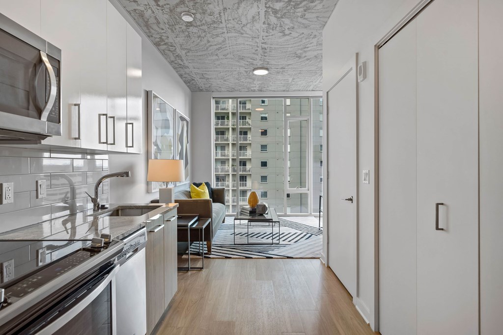 a kitchen with a view of a living room and a door to a balcony