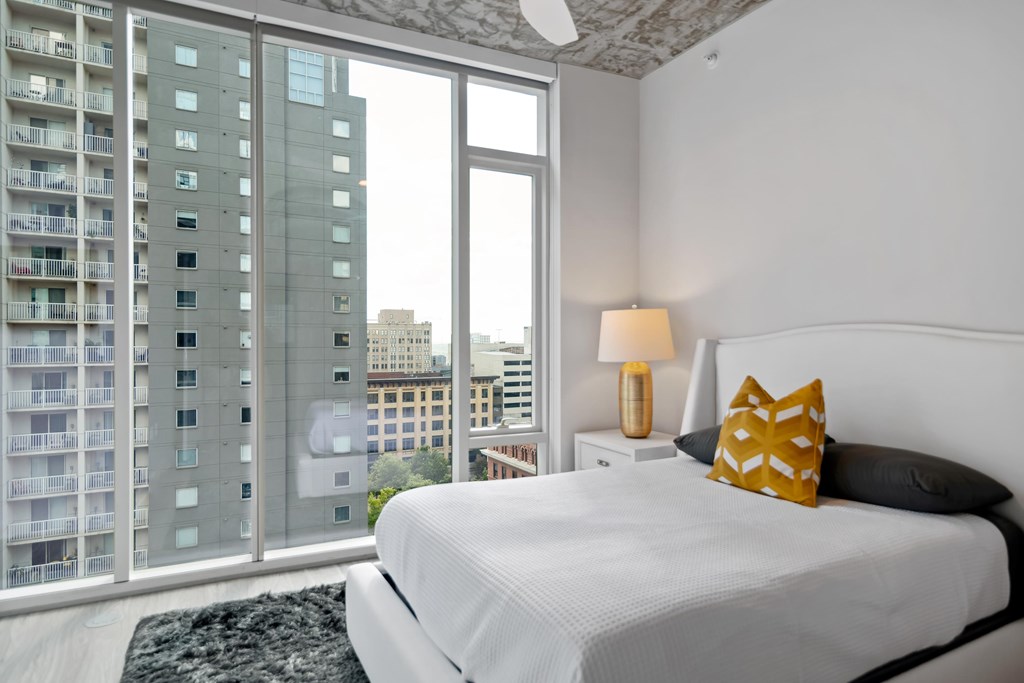 a bedroom with a large window and a white bed