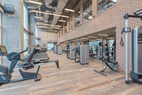 a gym with cardio equipment and weights in a building with brick walls