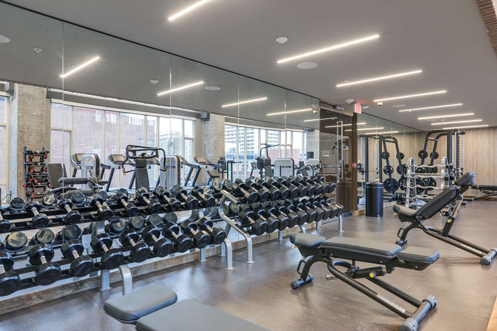 a gym with weights and cardio equipment on the floor and glass walls
