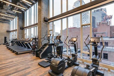 a gym with cardio machines and a view of the city