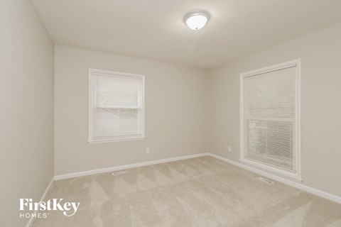 a bedroom with a carpeted floor and two windows