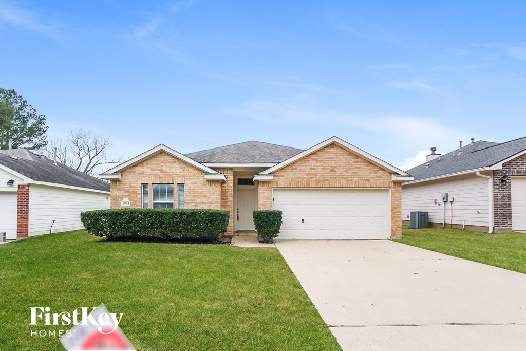 a white and brick house with a driveway and grass