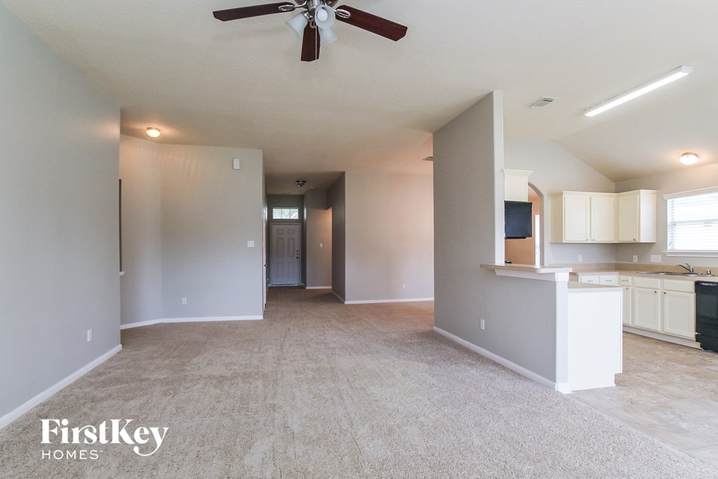an empty living room and kitchen with a ceiling fan