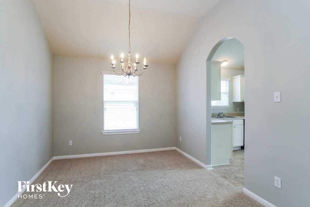 an empty dining room with a chandelier and a window
