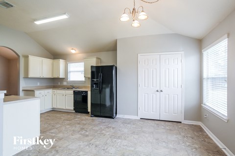 a kitchen with white cabinets and a black refrigerator