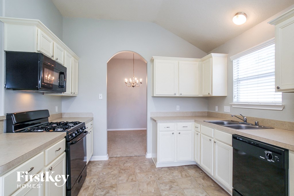 a kitchen with white cabinets and a black stove and a sink