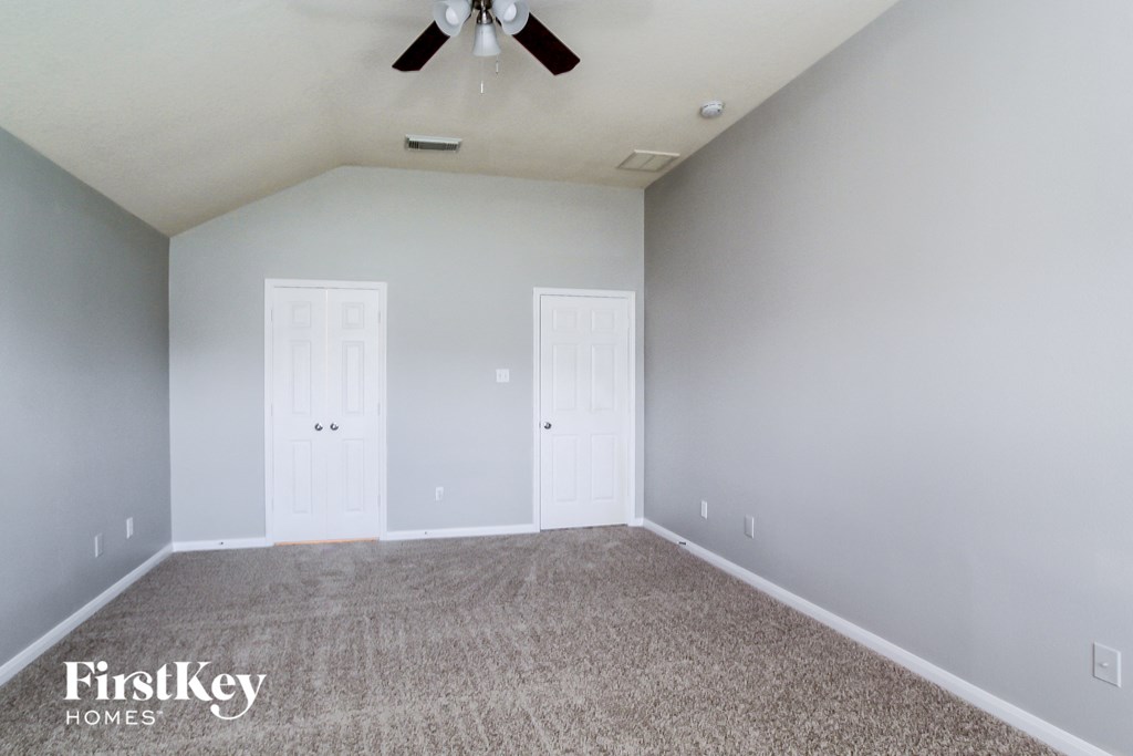 a empty room with a ceiling fan and white doors