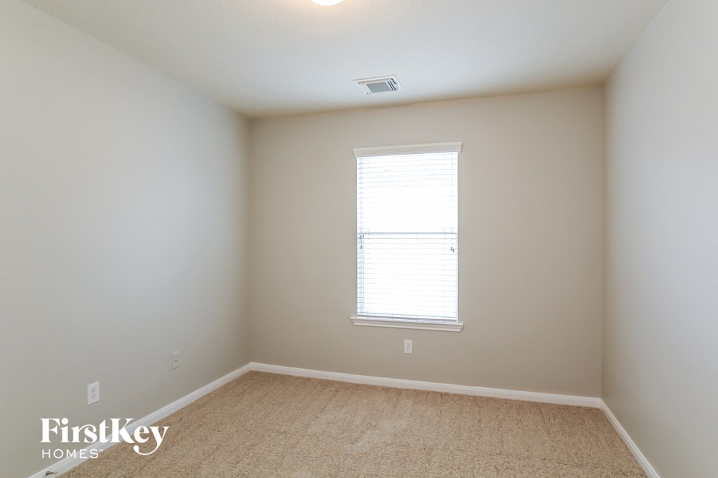 a bedroom with a window and a carpeted floor