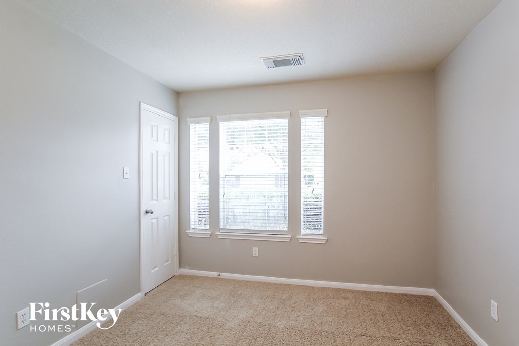 a bedroom with a window and a door and a carpeted floor