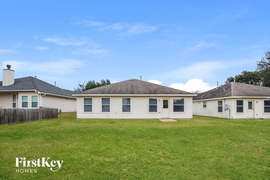 the backyard of a white house with a grassy yard