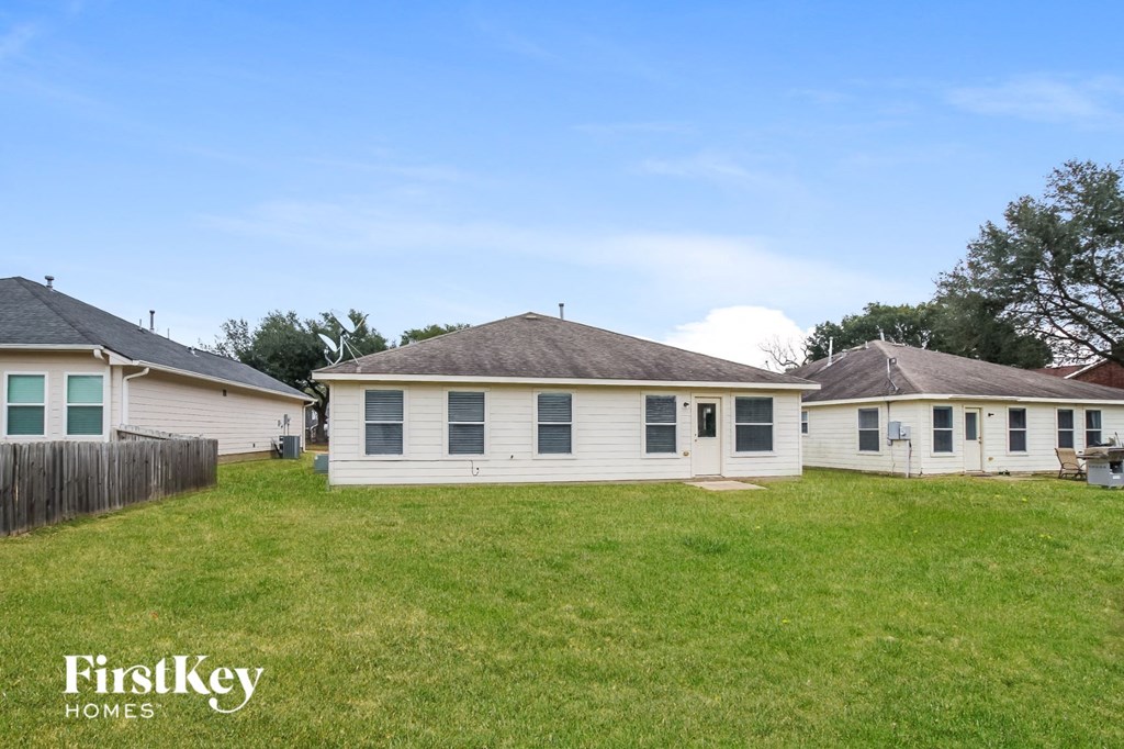 the backyard of a white house with a yard and a fence