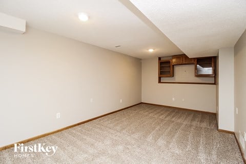 the living room is spacious and clean with carpet and a wall mounted tv