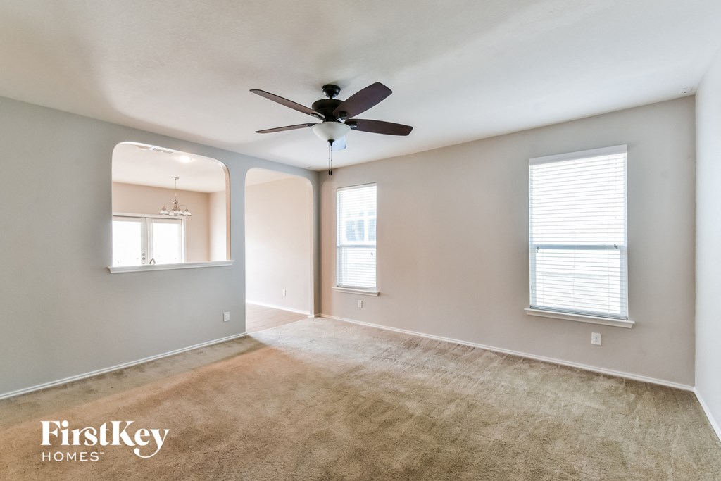 an empty living room with a ceiling fan and a window