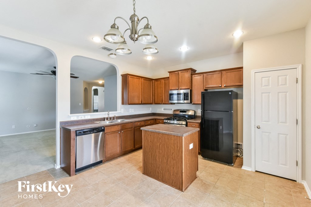 a kitchen with wooden cabinets and a black refrigerator and a sink