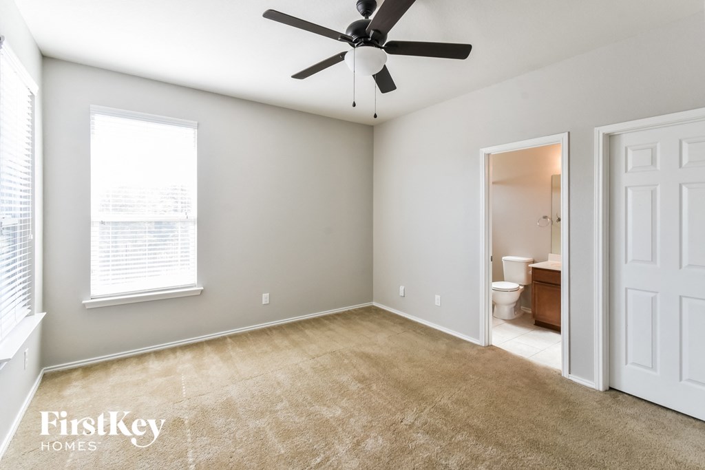 an empty living room with a ceiling fan and a bathroom
