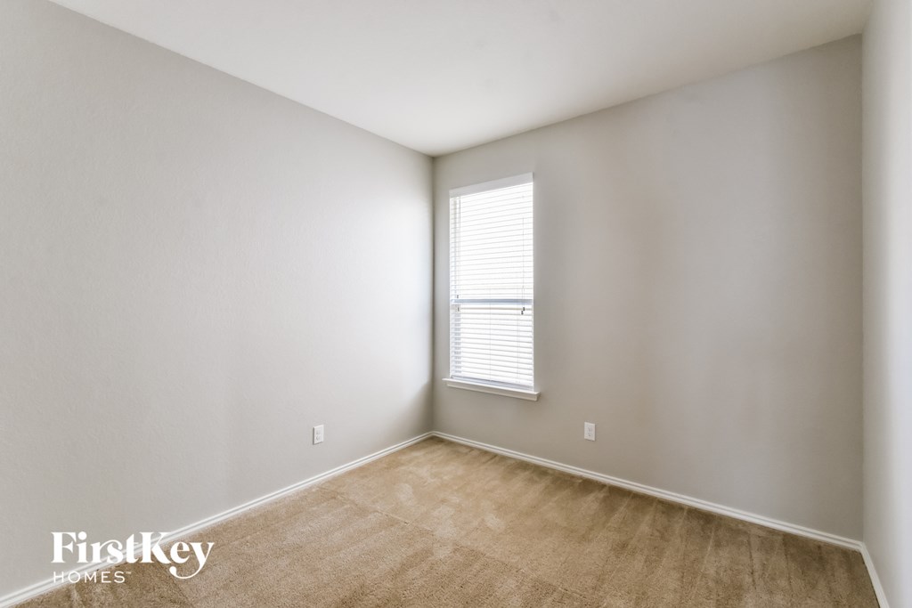 a bedroom with white walls and a window and a wooden floor