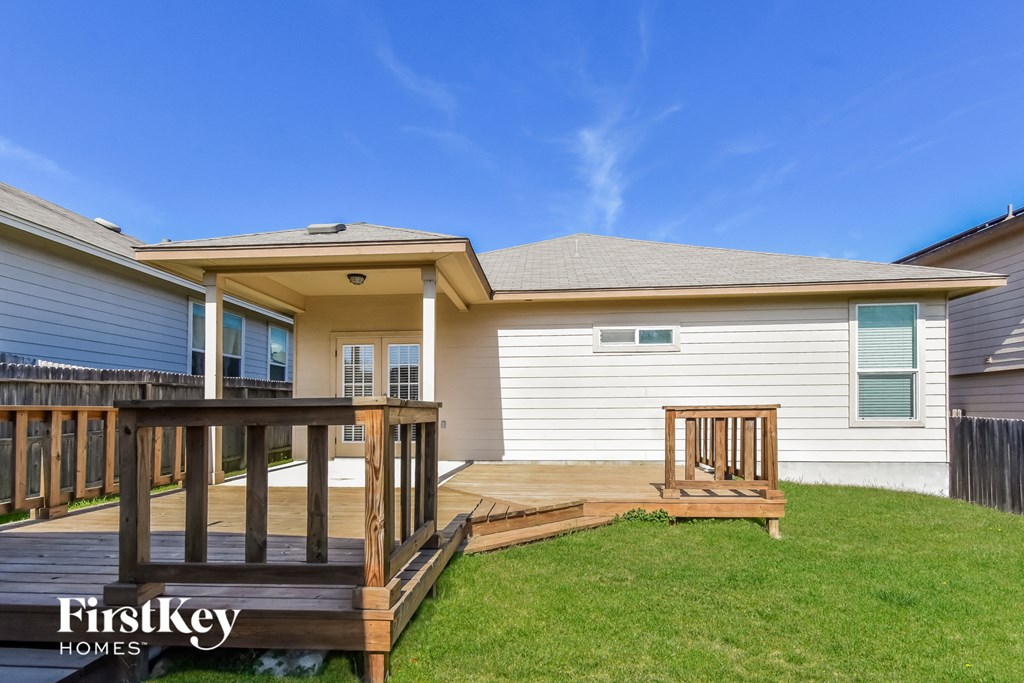 the backyard of a house with a wooden deck and a yard