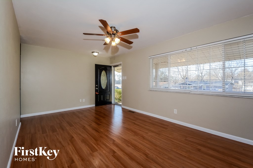 an empty living room with a ceiling fan and a large window