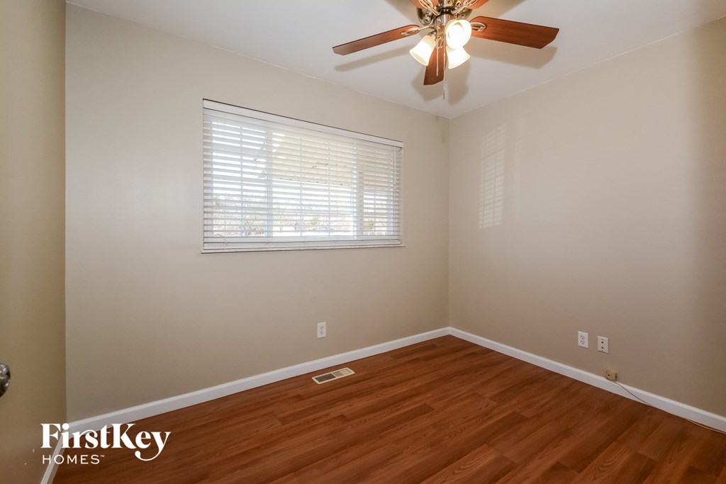 a bedroom with wood floors and a ceiling fan