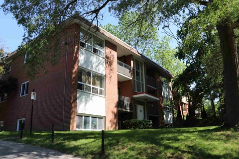 a red brick apartment building with green grass and trees