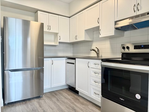 A modern kitchen with a stainless steel refrigerator, white cabinets, and a black oven.