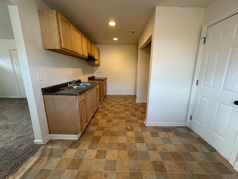 A kitchen with wooden cabinets and a checkered floor.