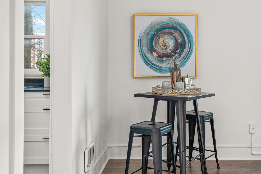 a dining room with three stools and a painting on the wall