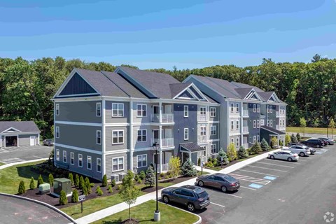 a rendering of an apartment building with cars parked in a parking lot