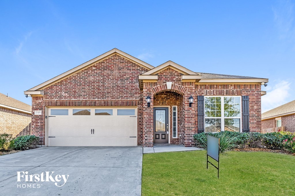 a brick house with a white garage door and a lawn