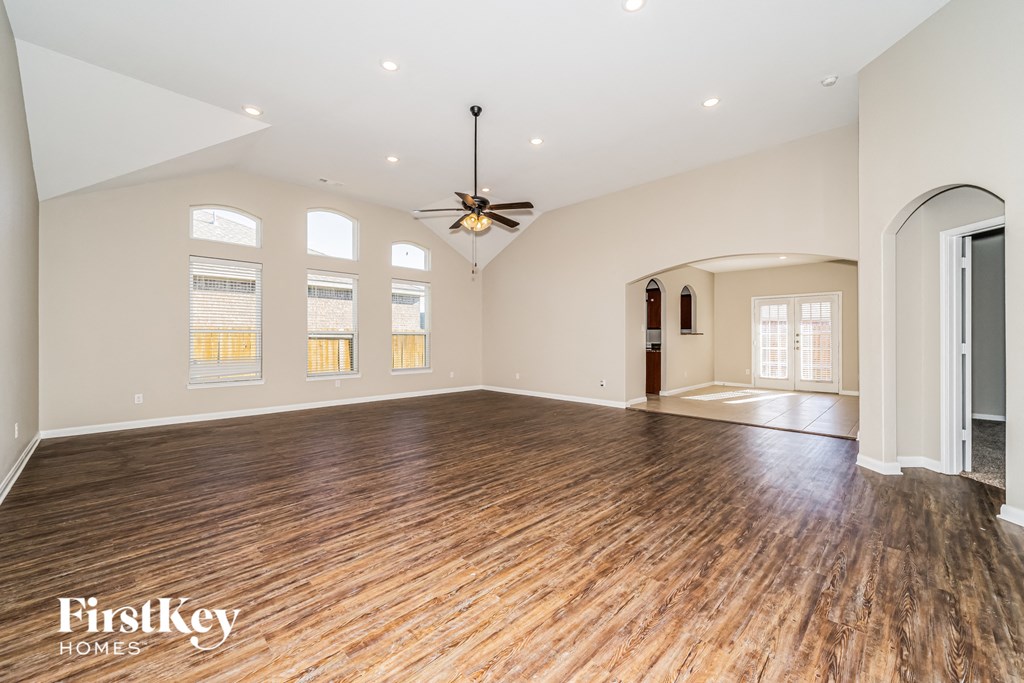 an empty living room with wood floors and a ceiling fan