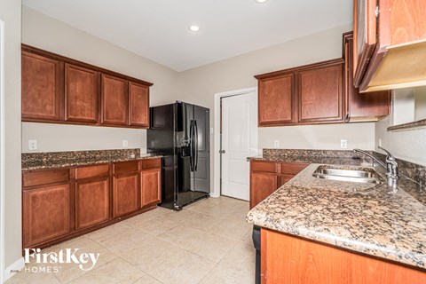 a kitchen with wood cabinets and granite counter tops and a black refrigerator