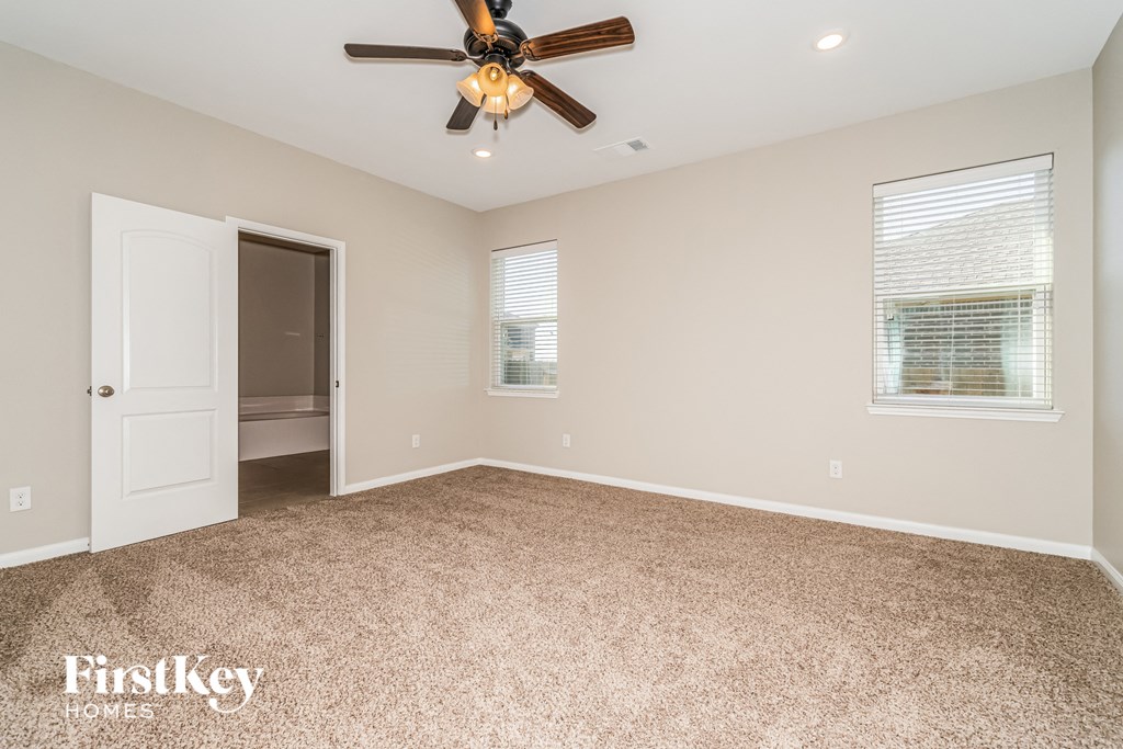 the master bedroom is spacious and clean with a ceiling fan
